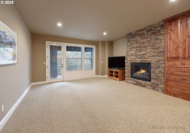 unfurnished living room with a stone fireplace and carpet