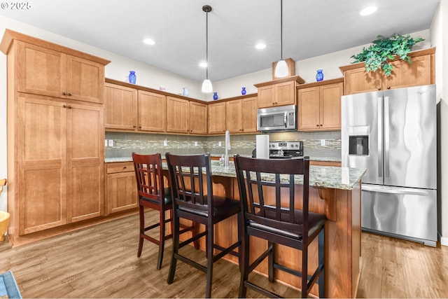 2741 25th Pl, Forest Grove, OR 97116 - kitchen with appliances with stainless steel finishes, light wood finished floors, tasteful backsplash, light stone counters, and decorative light fixtures