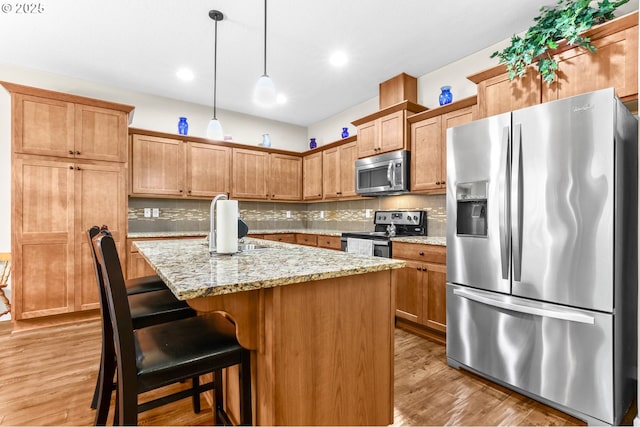 2741 25th Pl, Forest Grove, OR 97116 - kitchen featuring stainless steel appliances, decorative backsplash, light wood-style floors, light stone countertops, and pendant lighting
