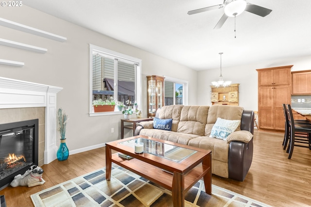 2741 25th Pl, Forest Grove, OR 97116 - living room with a chandelier, light wood-style flooring, a tiled fireplace, ceiling fan, and baseboards