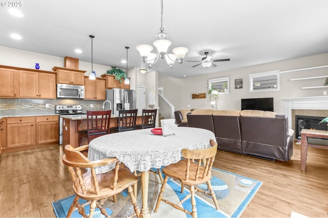 2741 25th Pl, Forest Grove, OR 97116 - dining room with light wood-style floors, ceiling fan, a chandelier, recessed lighting, and a fireplace