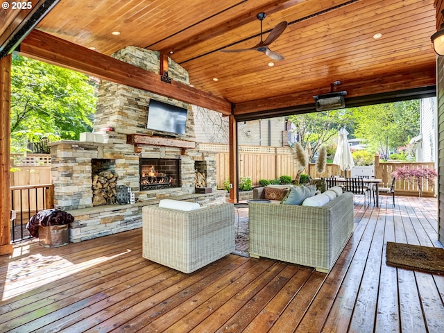 deck with ceiling fan, an outdoor living space with a fireplace, fence, and outdoor dining space