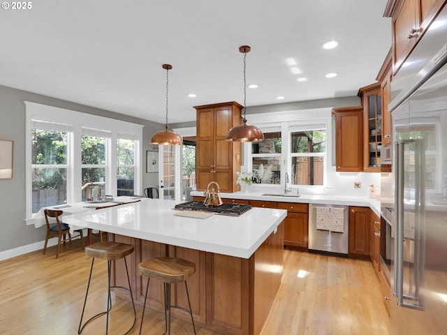 kitchen featuring light countertops, brown cabinetry, stainless steel appliances, and light wood finished floors
