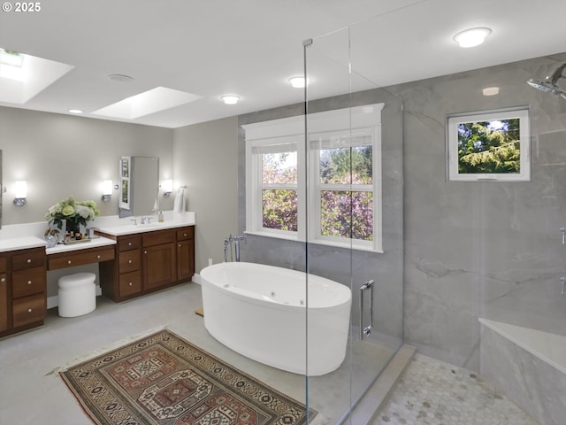 full bathroom with a skylight, a freestanding tub, a shower with shower door, and vanity