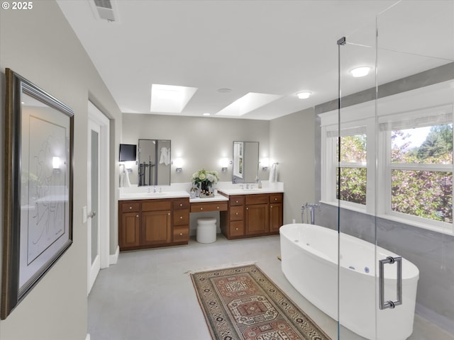 full bathroom featuring a skylight, a freestanding bath, vanity, and visible vents