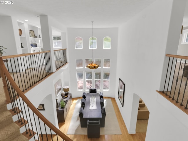 living room featuring light wood-style floors, a towering ceiling, a wealth of natural light, and a chandelier