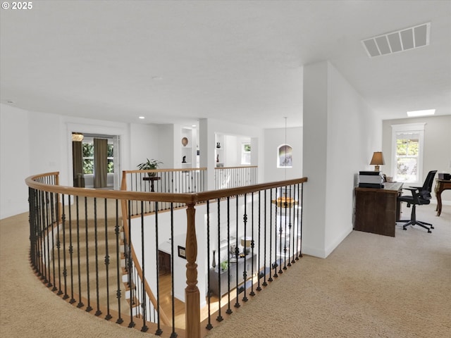 hall with visible vents, carpet, baseboards, and an upstairs landing