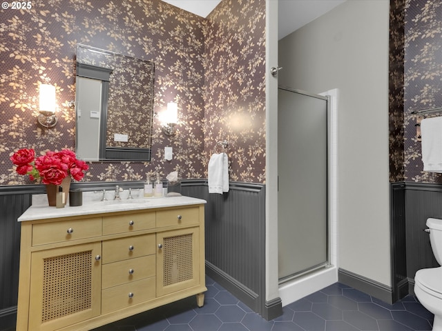 bathroom featuring toilet, wallpapered walls, and wainscoting