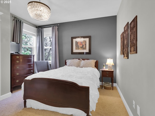 bedroom with light colored carpet, baseboards, and an inviting chandelier