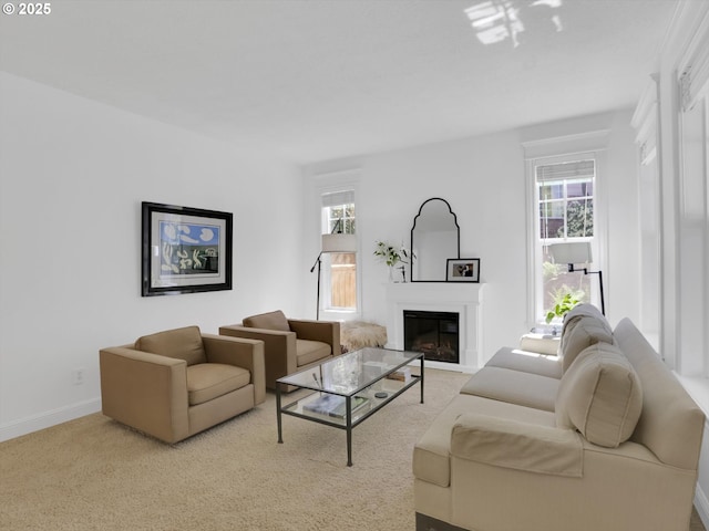 carpeted living area featuring baseboards and a glass covered fireplace