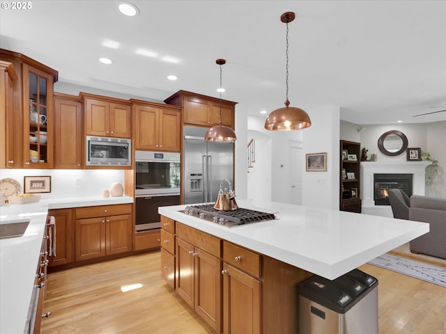 kitchen with brown cabinets, light wood finished floors, open floor plan, built in appliances, and recessed lighting