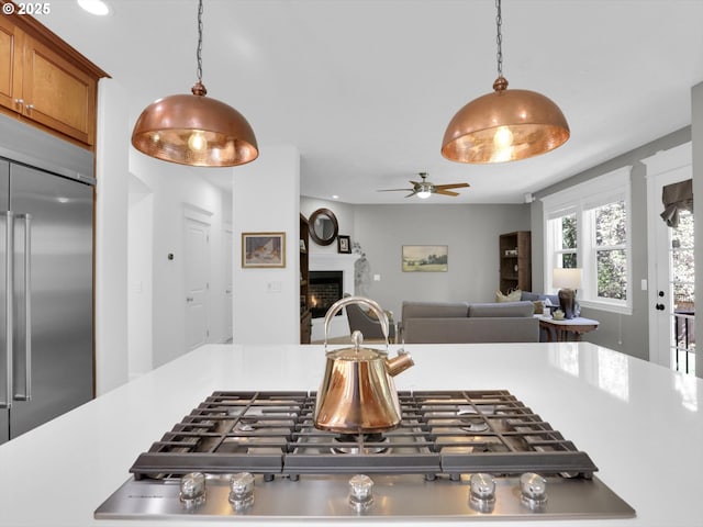 kitchen featuring light countertops, a lit fireplace, pendant lighting, and stainless steel built in fridge