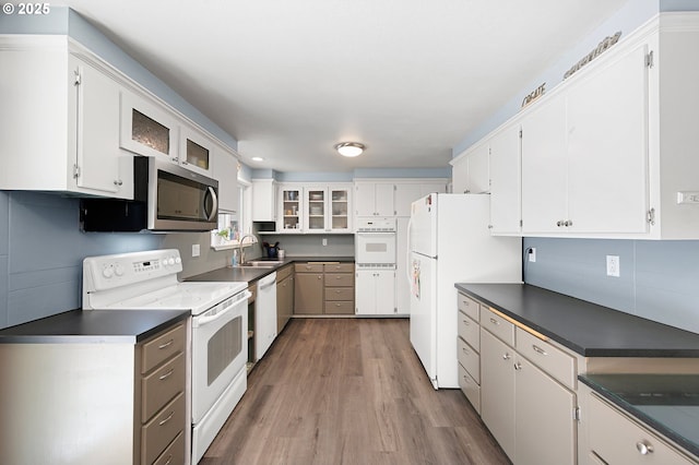 536 Kingswood Ave, Eugene, OR 97405 - kitchen with dark countertops, wood finished floors, a sink, glass insert cabinets, and white appliances