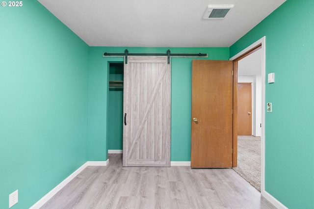 536 Kingswood Ave, Eugene, OR 97405 - unfurnished bedroom featuring a barn door, baseboards, wood finished floors, and visible vents