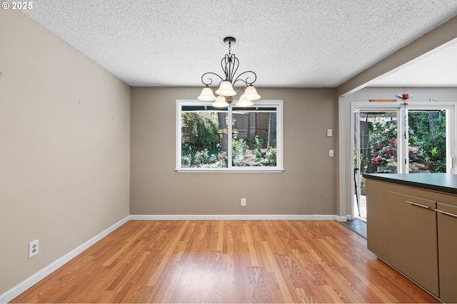 536 Kingswood Ave, Eugene, OR 97405 - unfurnished dining area featuring light wood-style floors, baseboards, a textured ceiling, and a chandelier