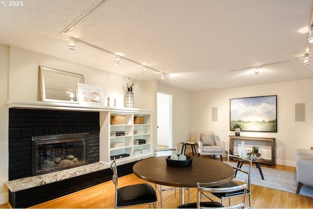 2440 SW Burbank Ave, Portland, OR 97225 - dining space with track lighting, wood finished floors, a fireplace, and a textured ceiling