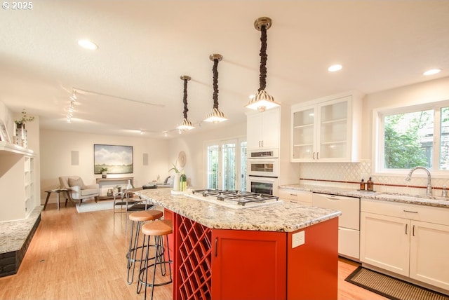 2440 SW Burbank Ave, Portland, OR 97225 - kitchen featuring white appliances, decorative backsplash, white cabinets, a center island, and a kitchen bar