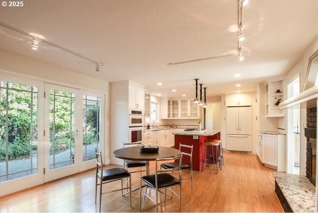 2440 SW Burbank Ave, Portland, OR 97225 - dining room featuring track lighting, light wood finished floors, recessed lighting, and a brick fireplace