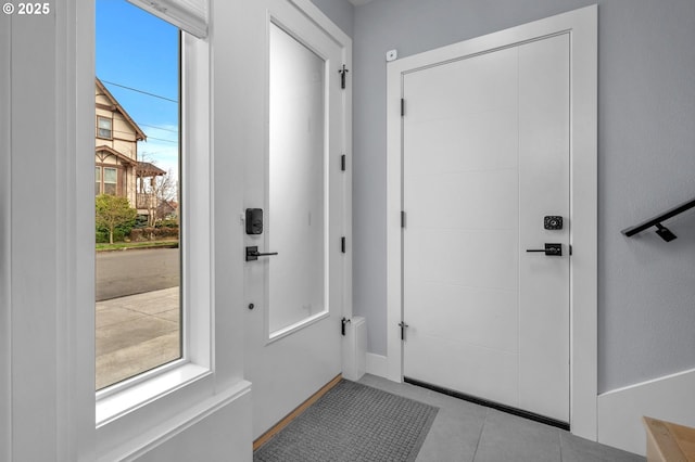 doorway with tile patterned floors and baseboards