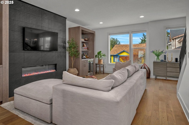 living room with recessed lighting, a fireplace, and light wood-type flooring