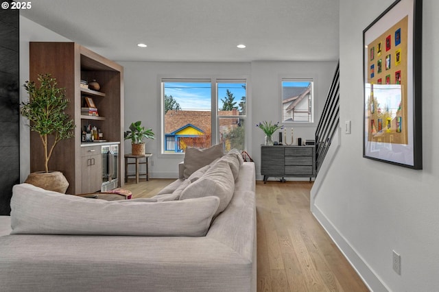 living room with recessed lighting, light wood-type flooring, baseboards, and stairs