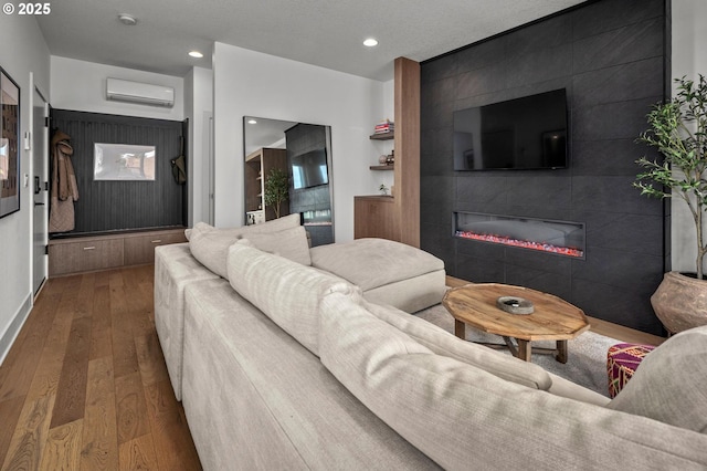 living area with recessed lighting, a tile fireplace, a wall unit AC, and hardwood / wood-style flooring