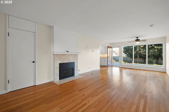 unfurnished living room featuring ceiling fan, a fireplace, and light hardwood / wood-style floors