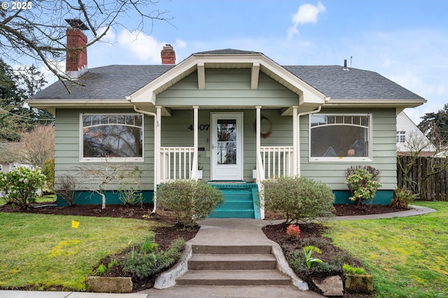 bungalow-style home with a porch, a shingled roof, a front lawn, and fence