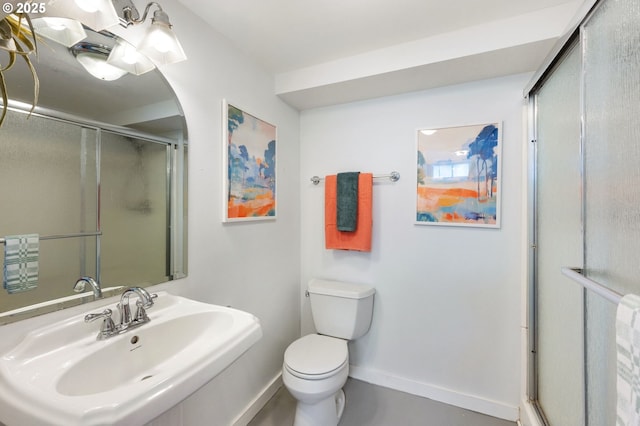 full bathroom featuring a sink, baseboards, a shower with shower door, and toilet