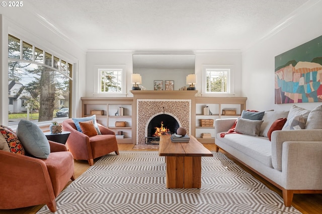 living area featuring a wealth of natural light, a tile fireplace, light wood-style floors, and ornamental molding