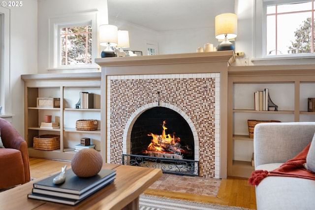 sitting room with crown molding, wood finished floors, a wealth of natural light, and a tile fireplace