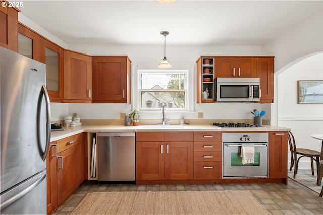 kitchen featuring light countertops, brown cabinetry, appliances with stainless steel finishes, and a sink