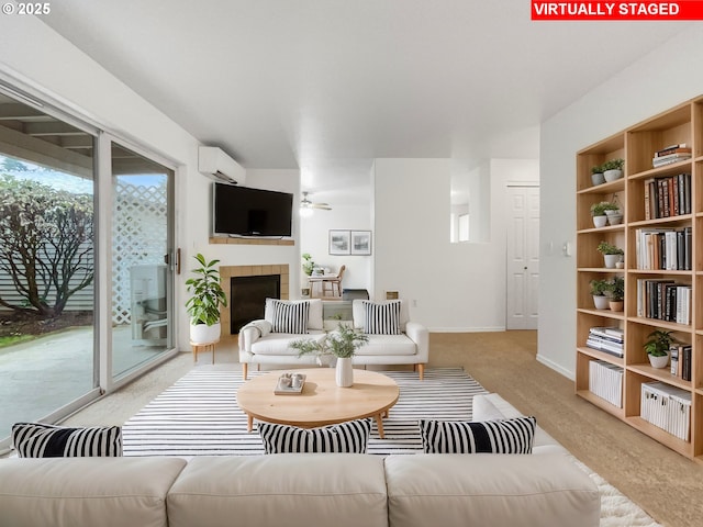 living area featuring a wall unit AC, a ceiling fan, baseboards, a tile fireplace, and light carpet