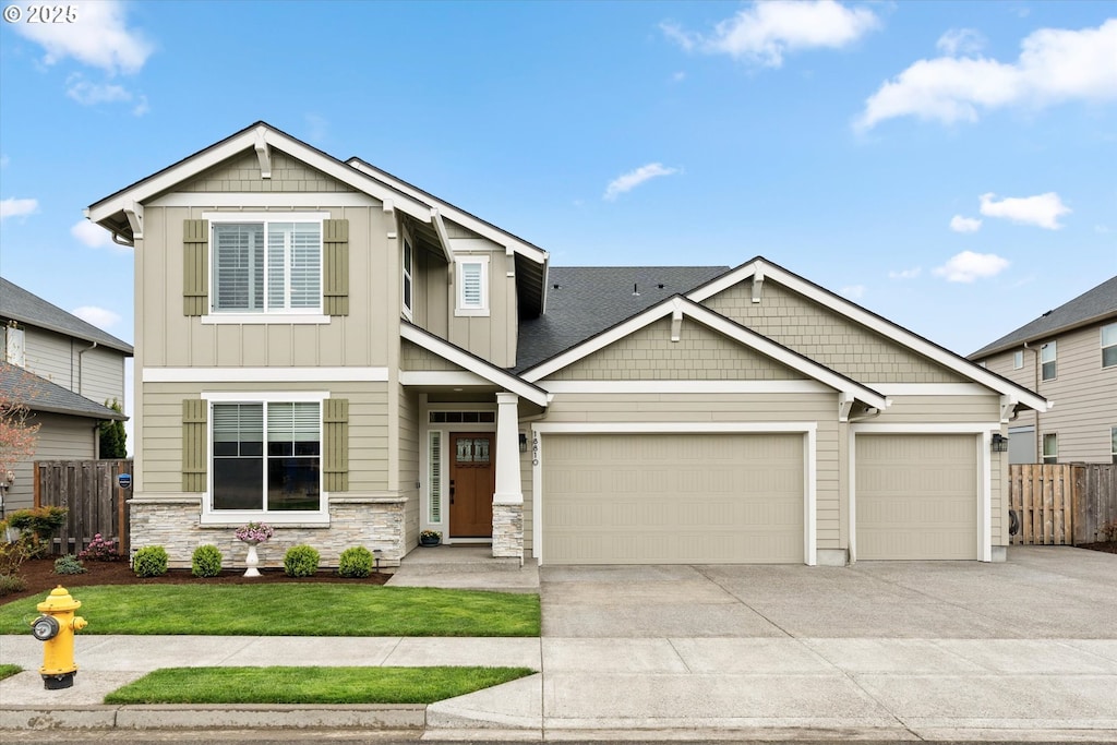 craftsman-style house with stone siding, board and batten siding, concrete driveway, an attached garage, and fence
