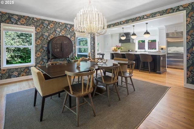 dining room with wallpapered walls, a chandelier, crown molding, light wood-style floors, and baseboards