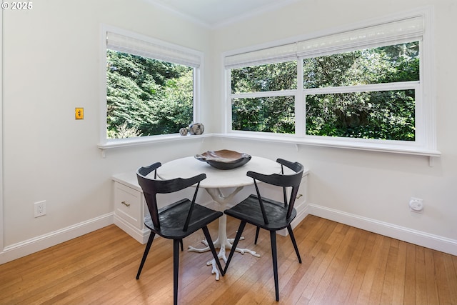 dining room with light wood-style floors, baseboards, and crown molding