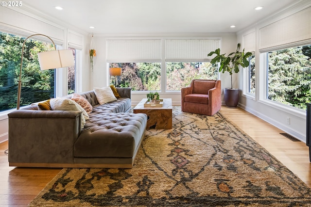 living room featuring light wood finished floors, ornamental molding, baseboards, and recessed lighting