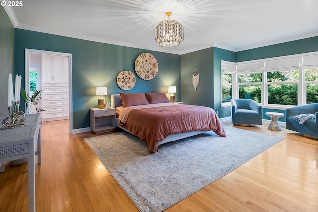 bedroom with multiple windows, a chandelier, wood finished floors, crown molding, and baseboards