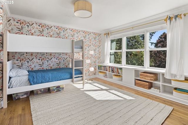 bedroom with wallpapered walls, ornamental molding, and wood finished floors