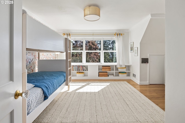 bedroom with wood finished floors and ornamental molding