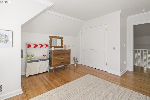 bedroom featuring wood finished floors, baseboards, crown molding, a closet, and vaulted ceiling