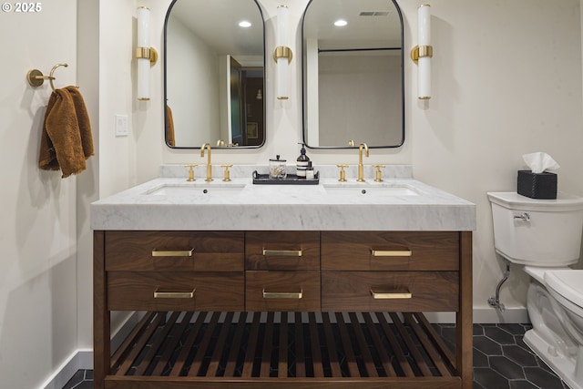 full bath with toilet, baseboards, double vanity, and tile patterned floors