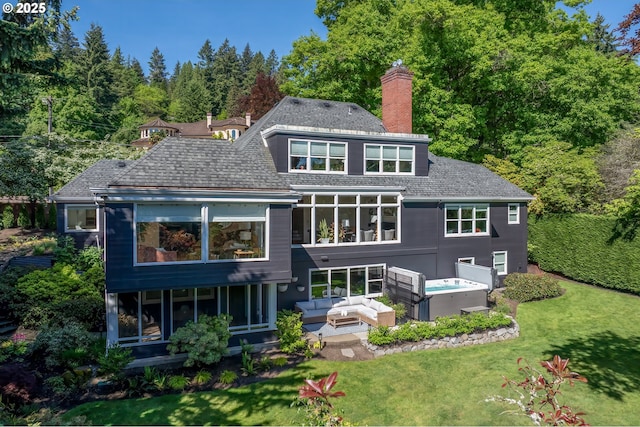 back of property with outdoor lounge area, a chimney, a lawn, and a sunroom