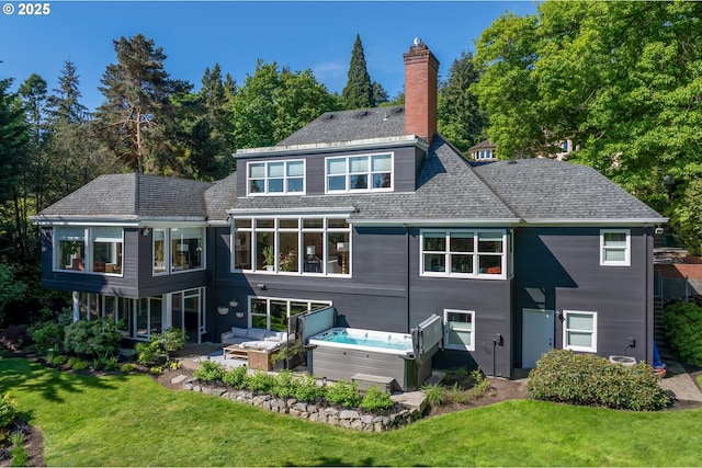 rear view of property featuring a lawn, a patio area, a chimney, and a hot tub
