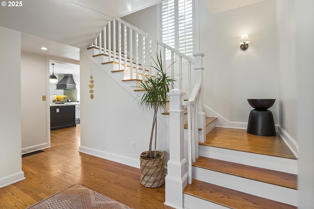 stairway with wood finished floors, recessed lighting, and baseboards