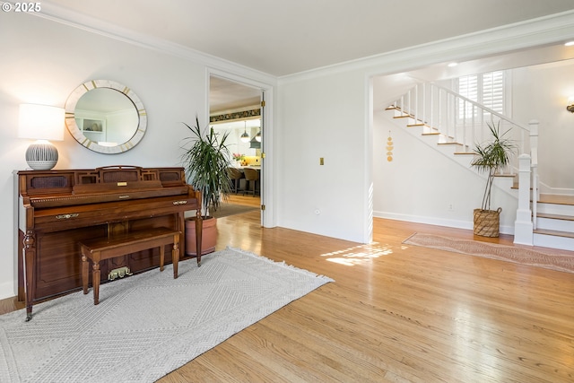 living area featuring stairs, wood finished floors, ornamental molding, and baseboards
