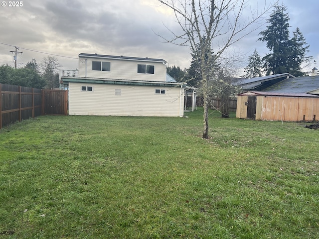 rear view of house with a lawn and a storage unit