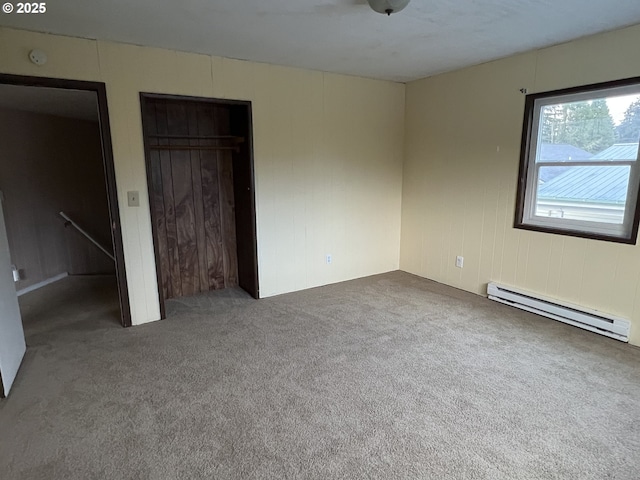 unfurnished bedroom with carpet floors, baseboard heating, and a closet