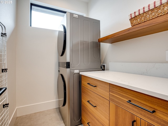 522 NE Province Dr, Camas, WA 98607 - laundry room featuring stacked washer / drying machine, cabinet space, light tile patterned flooring, and baseboards