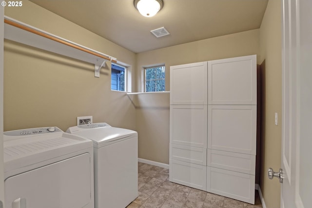 clothes washing area featuring cabinets and washing machine and clothes dryer